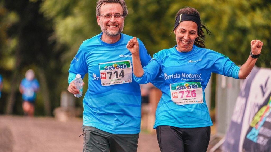 Two joyful runners crossing the finish line in a marathon race outdoors.
